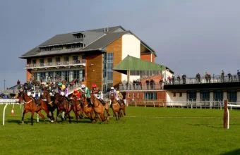Horses round the bend after passing the Carlisle stands