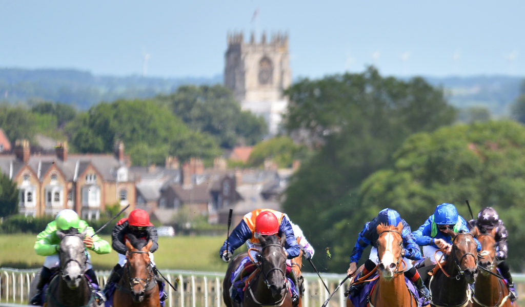 Horses in running at Beverley racecourse with the church in the distance