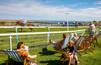 People watching a race on deckchairs with the sea in the distance