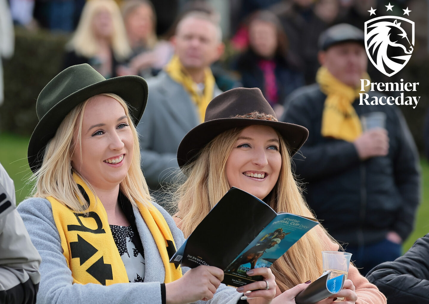 Two female fans with free Betfair scarves reading the racecards