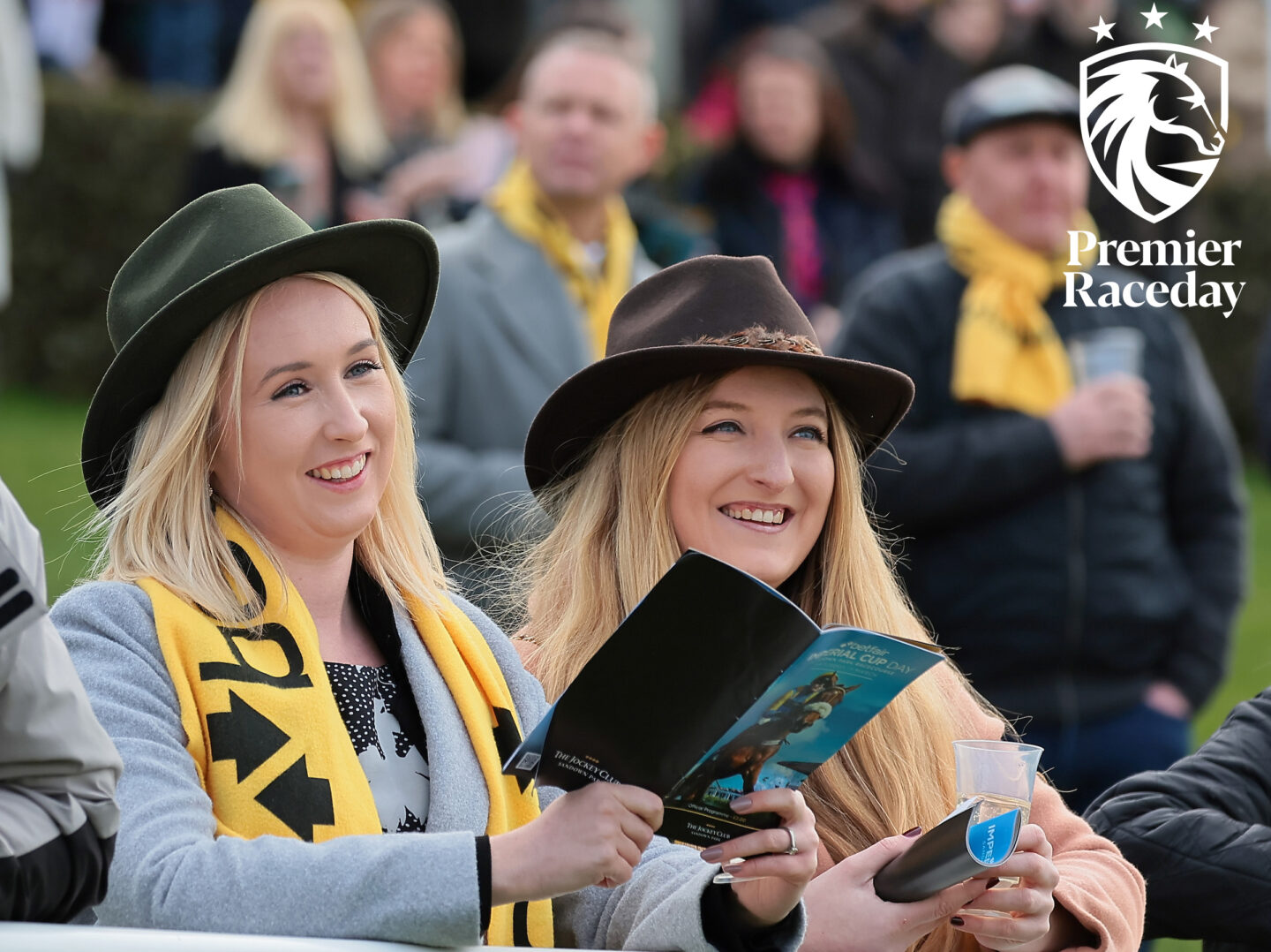 Two female fans with free Betfair scarves reading the racecards