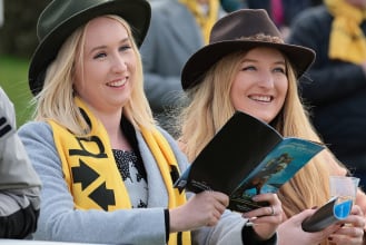 Two female fans with free Betfair scarves reading the racecards